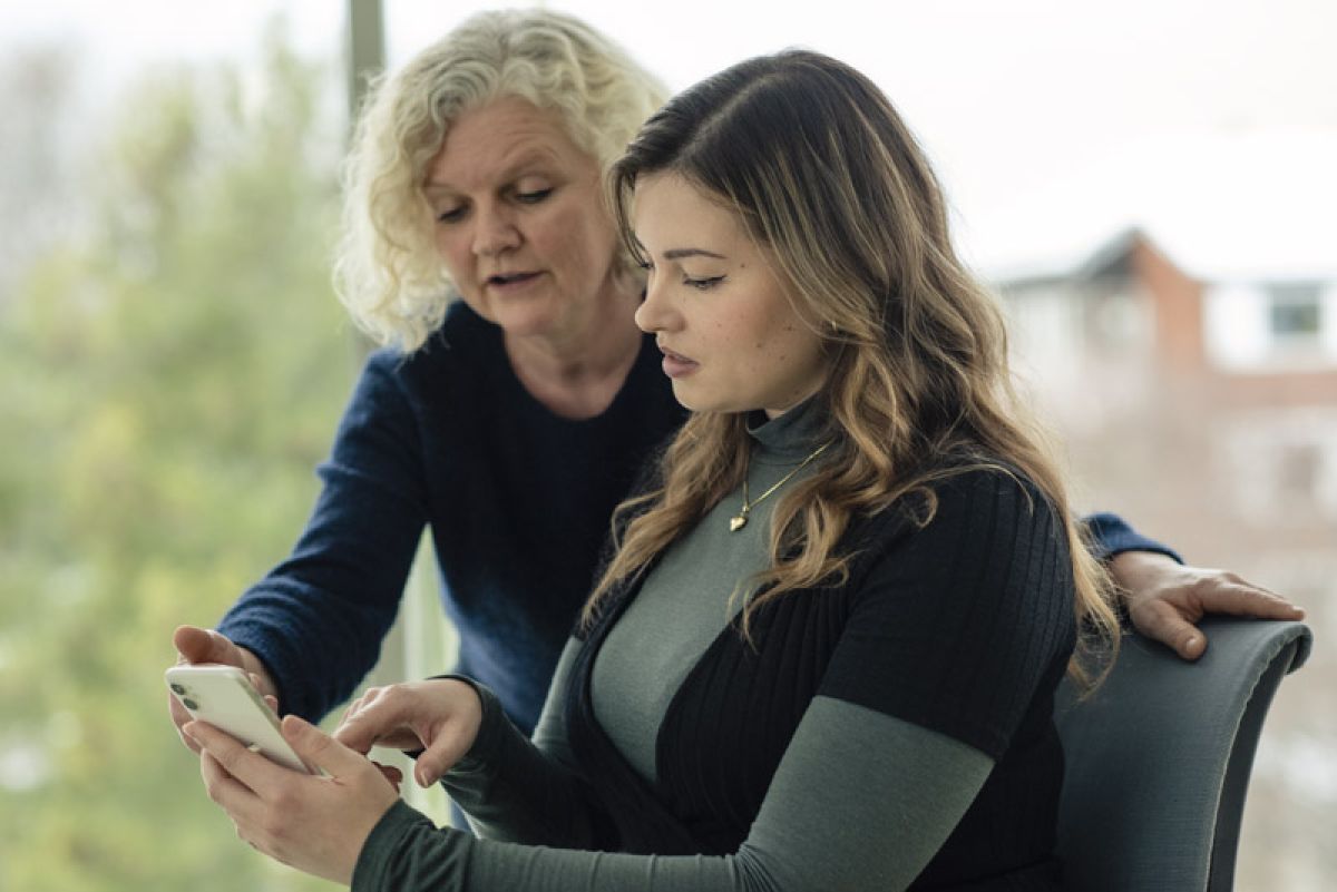 Two women are looking at a mobile phone